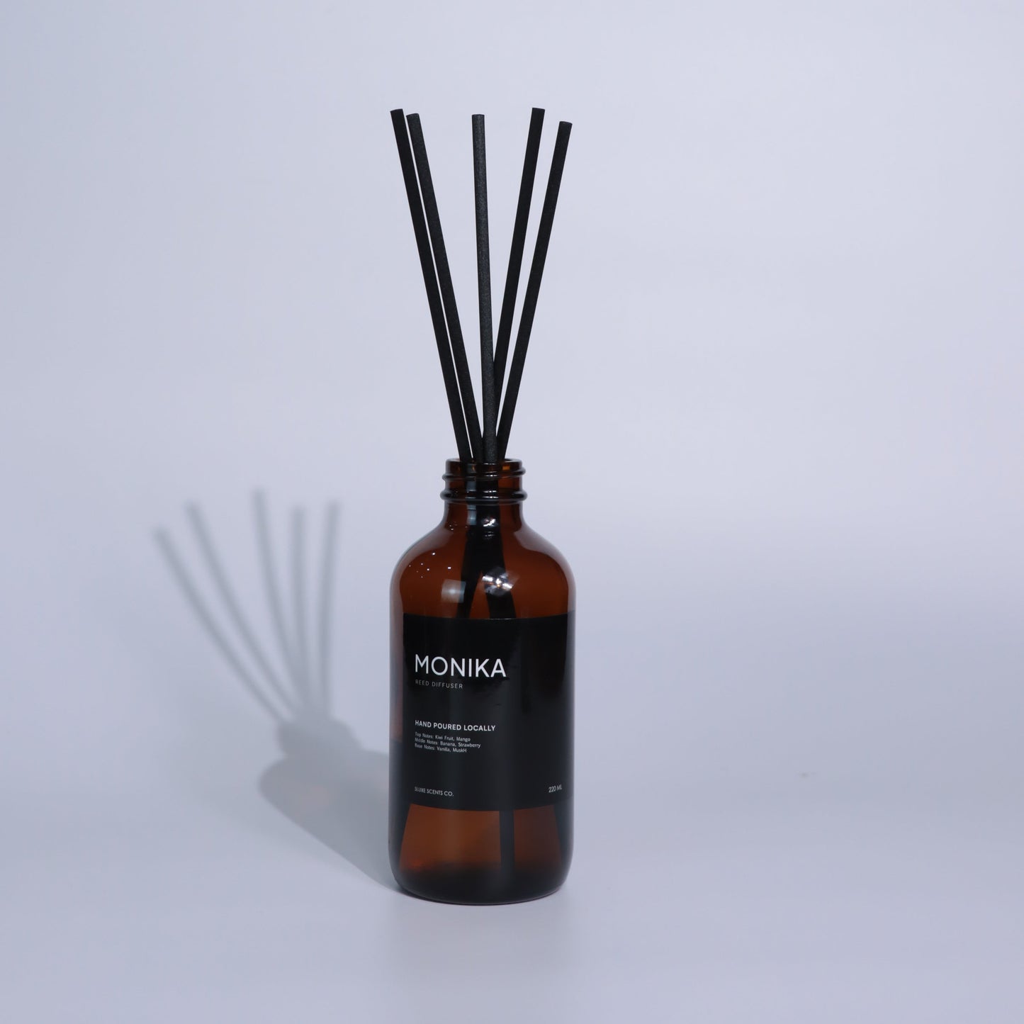 Reed diffuser with a brown bottle and black sticks on a white background