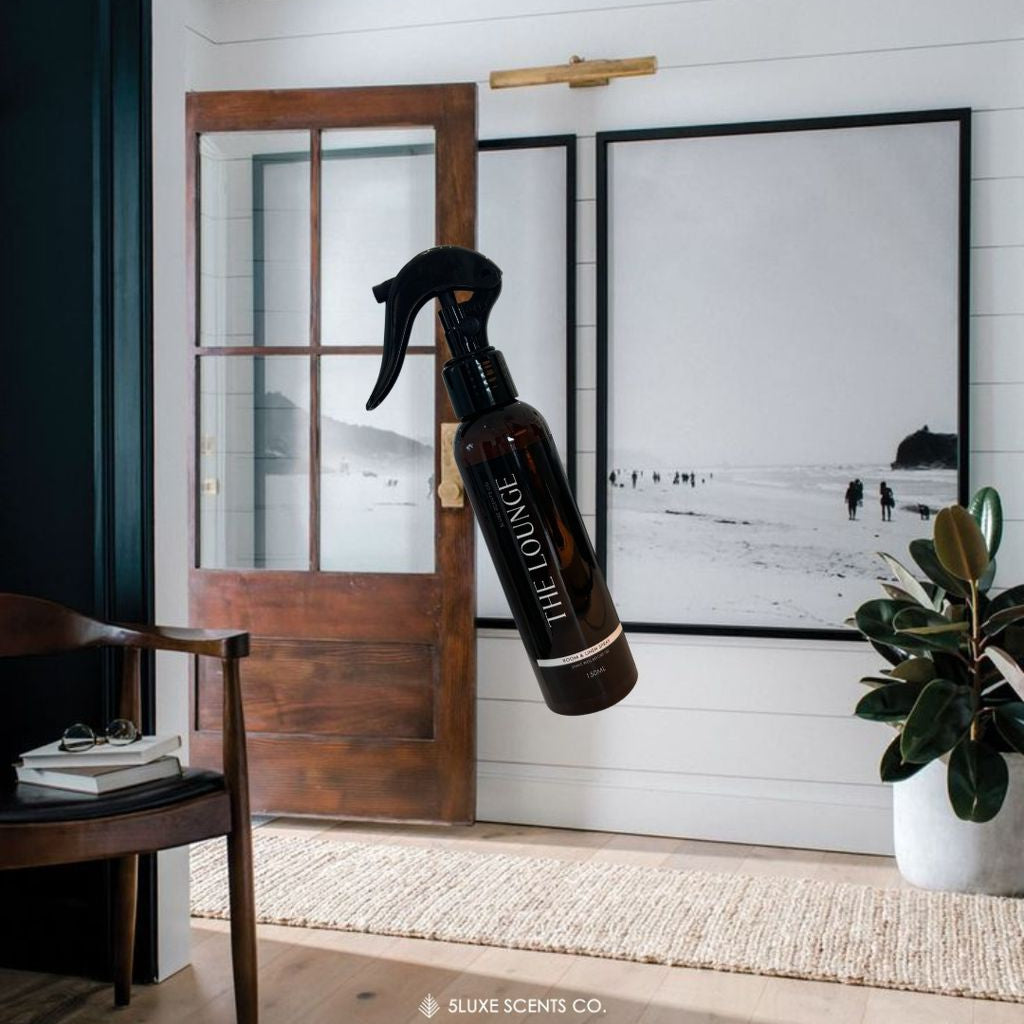 Spray bottle with a brand logo in a room with wooden door and framed pictures.